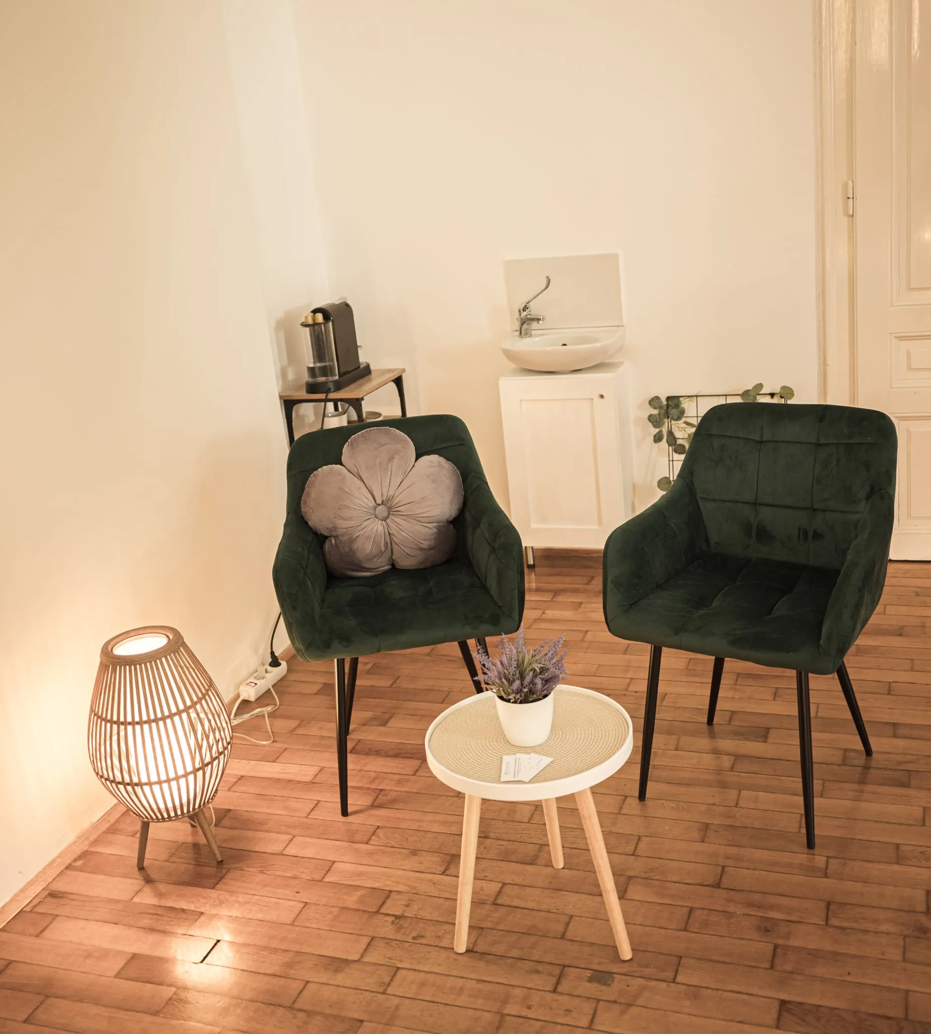 Várósarok két zöld bársonyfotellel, kis kerek asztallal és rattan lámpával
