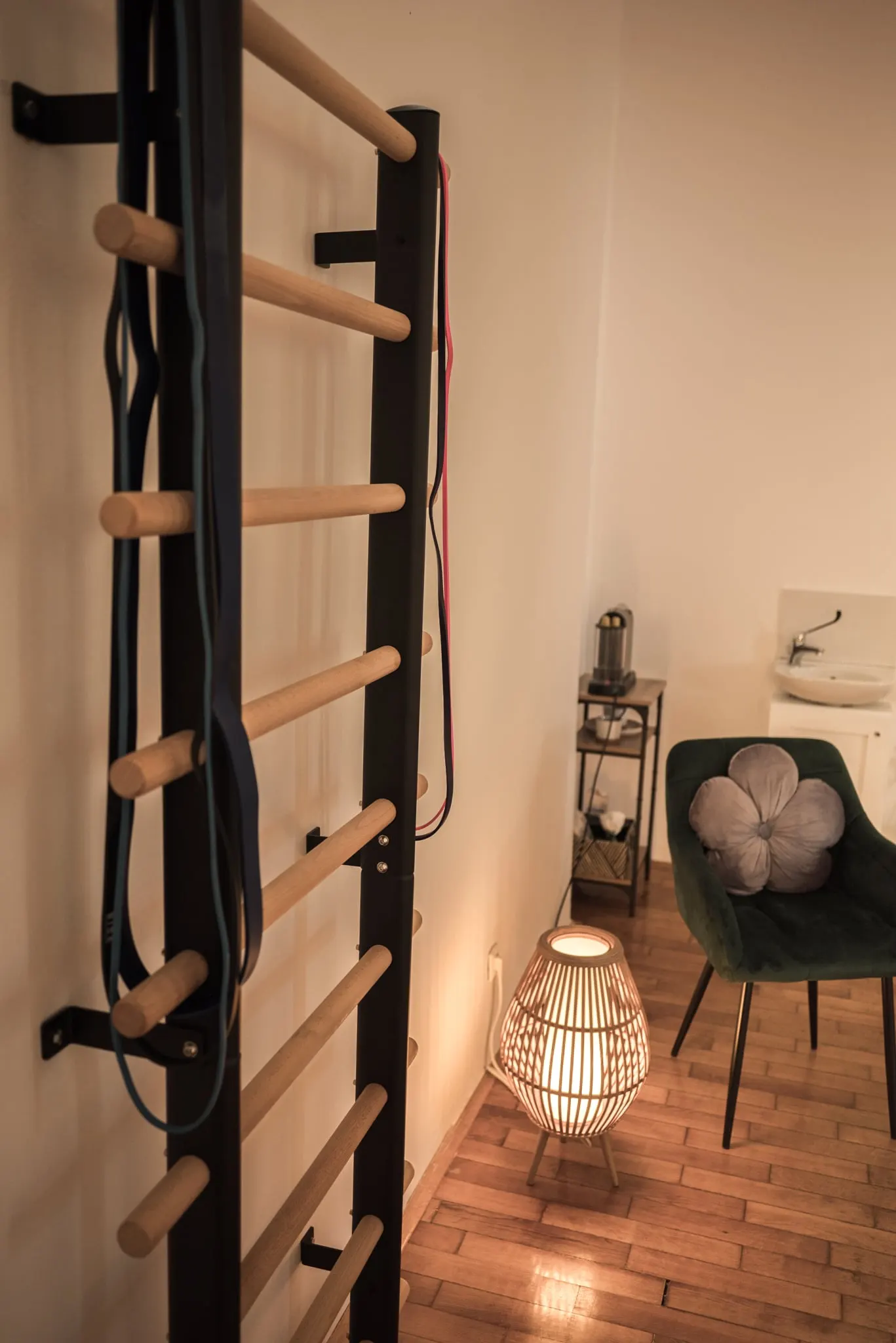 Fa bordásfal a terem falán, mellette rattan lámpa és zöld fotel